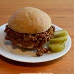 sloppy joe on white plate with pickle slices