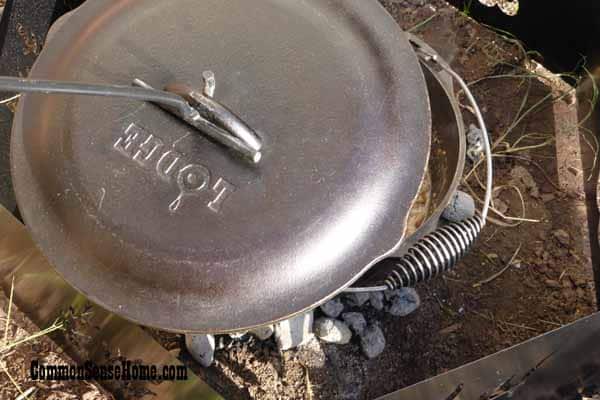 Lifting the lid of a cast iron Dutch oven with a lid lifter