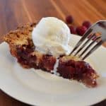 cranberry walnut pie with ice cream on white plate