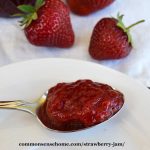 strawberry jam on a spoon on a white plate with strawberries in the background