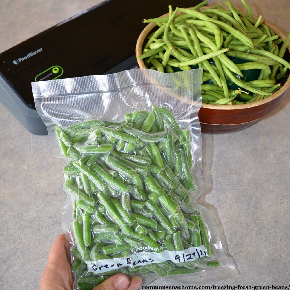 freezing green beans - vacuum sealed package of green beans with fresh green beans and vacuum sealer in background