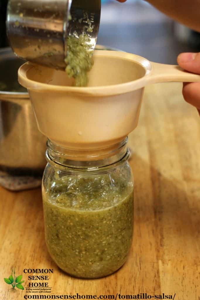 filling mason jar with salsa verde for canning tomatillo salsa