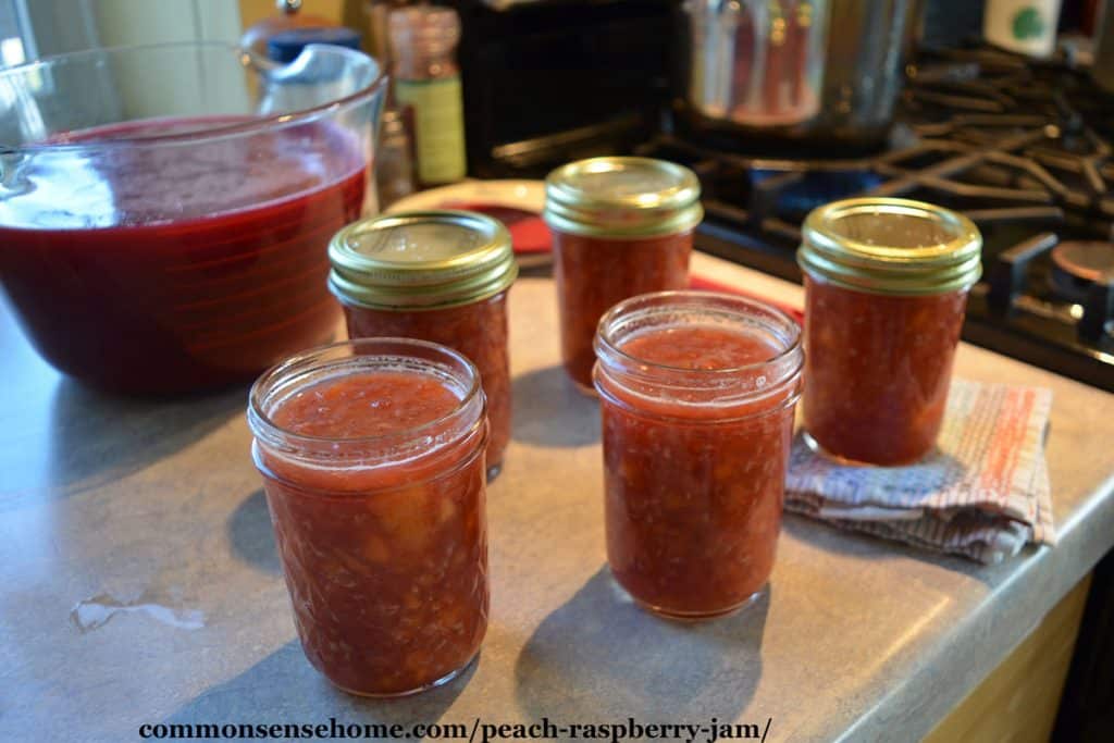 jars of peach raspberry jam being filled on counter