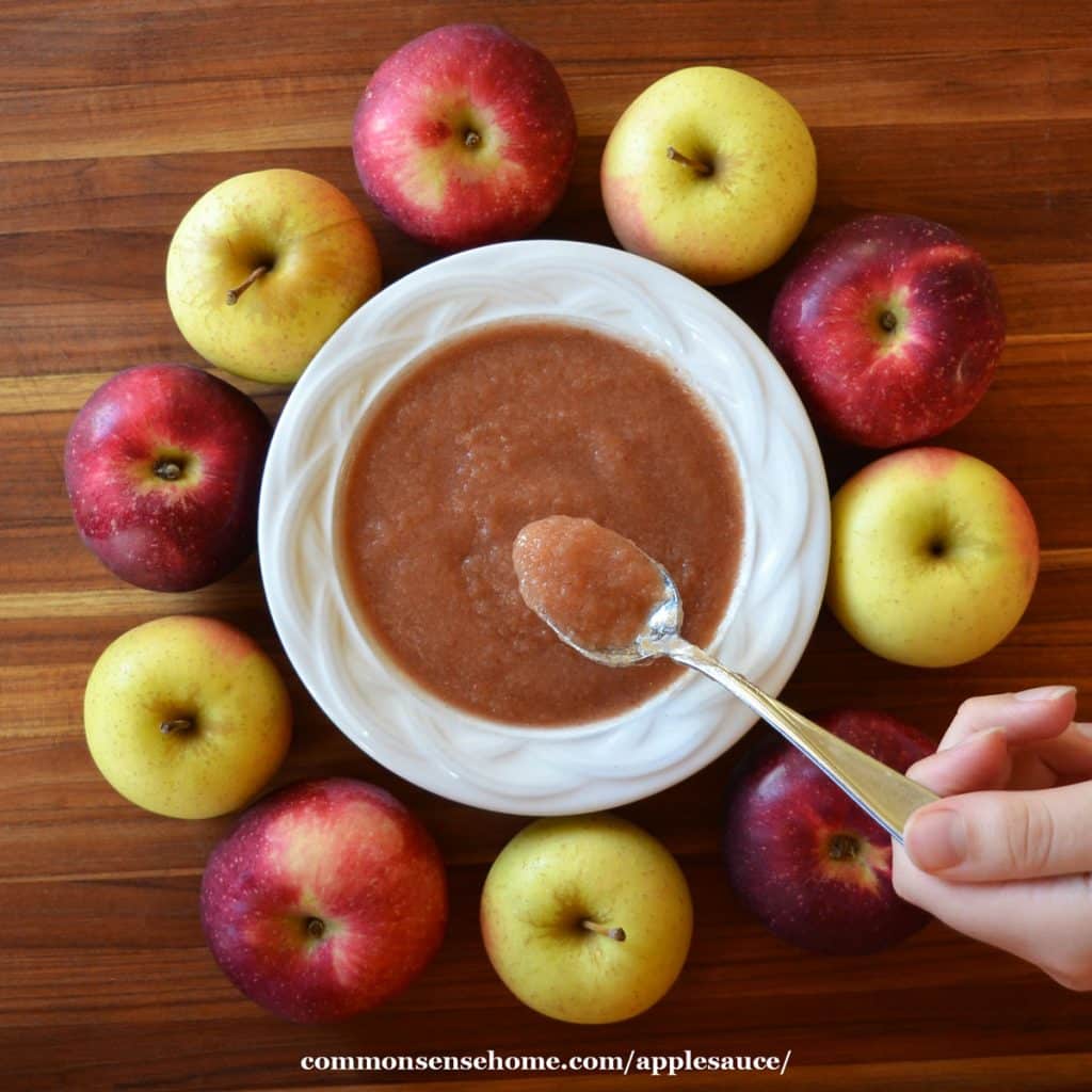 applesauce in bowl surrounded by apples