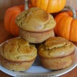 pumpkin muffins on white plate with mini pumpkin behind