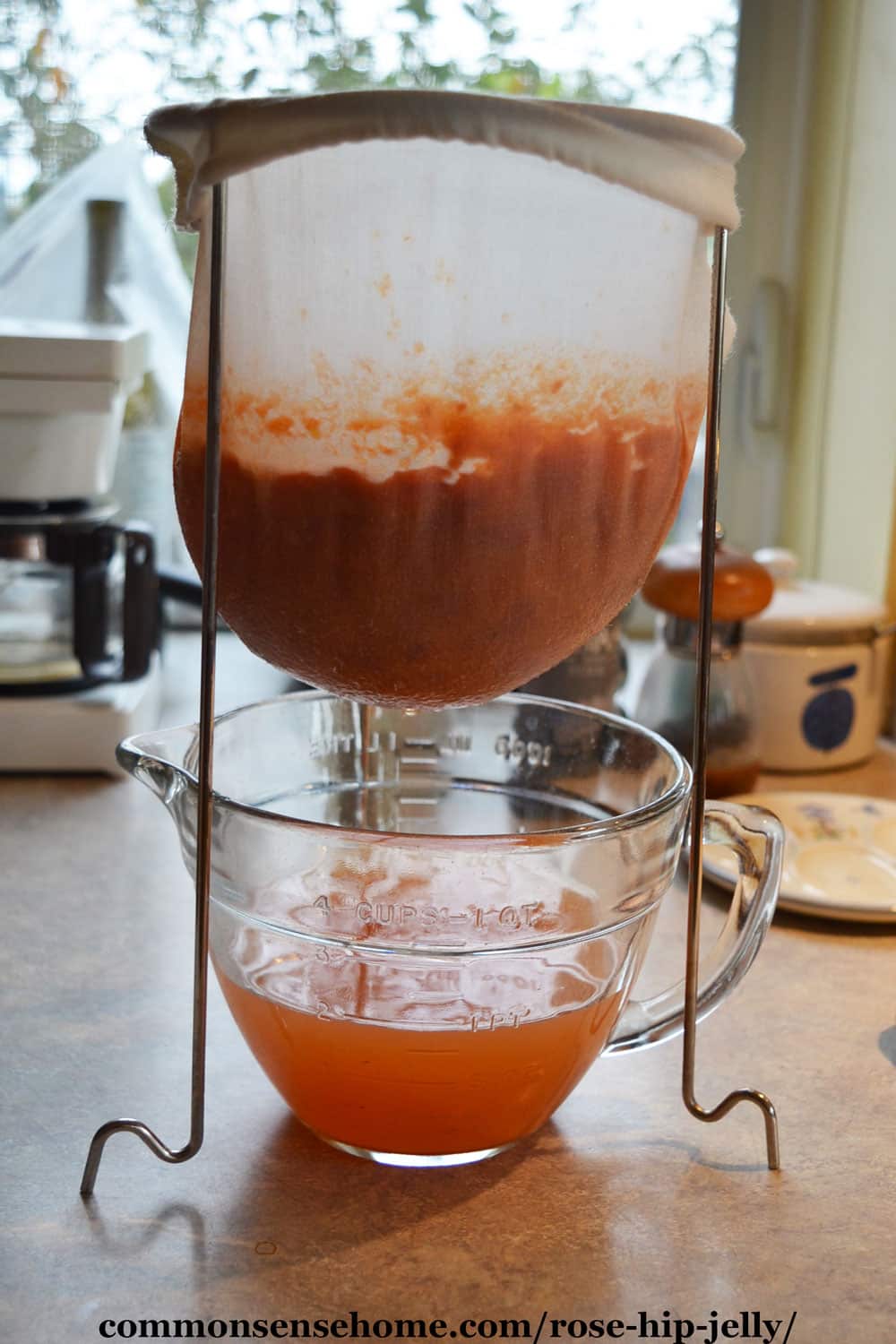straining rose hip juice in a jelly bag