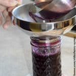 filling mason jar with homemade elderberry syrup