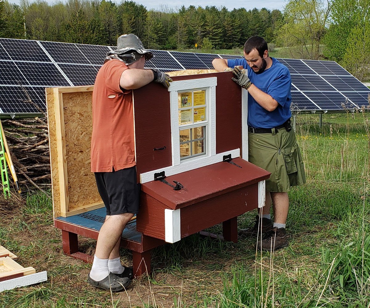 two young men assembling a chicken coop