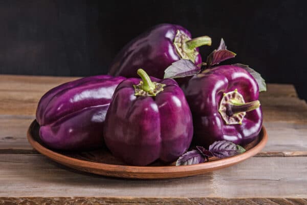 wooden bowl of purple peppers and purple basil