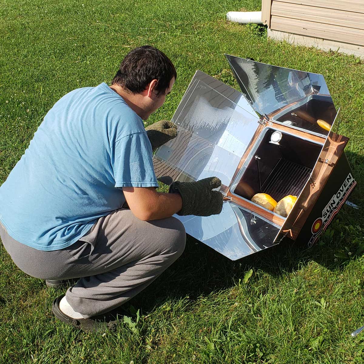 young man cooking with a solar oven