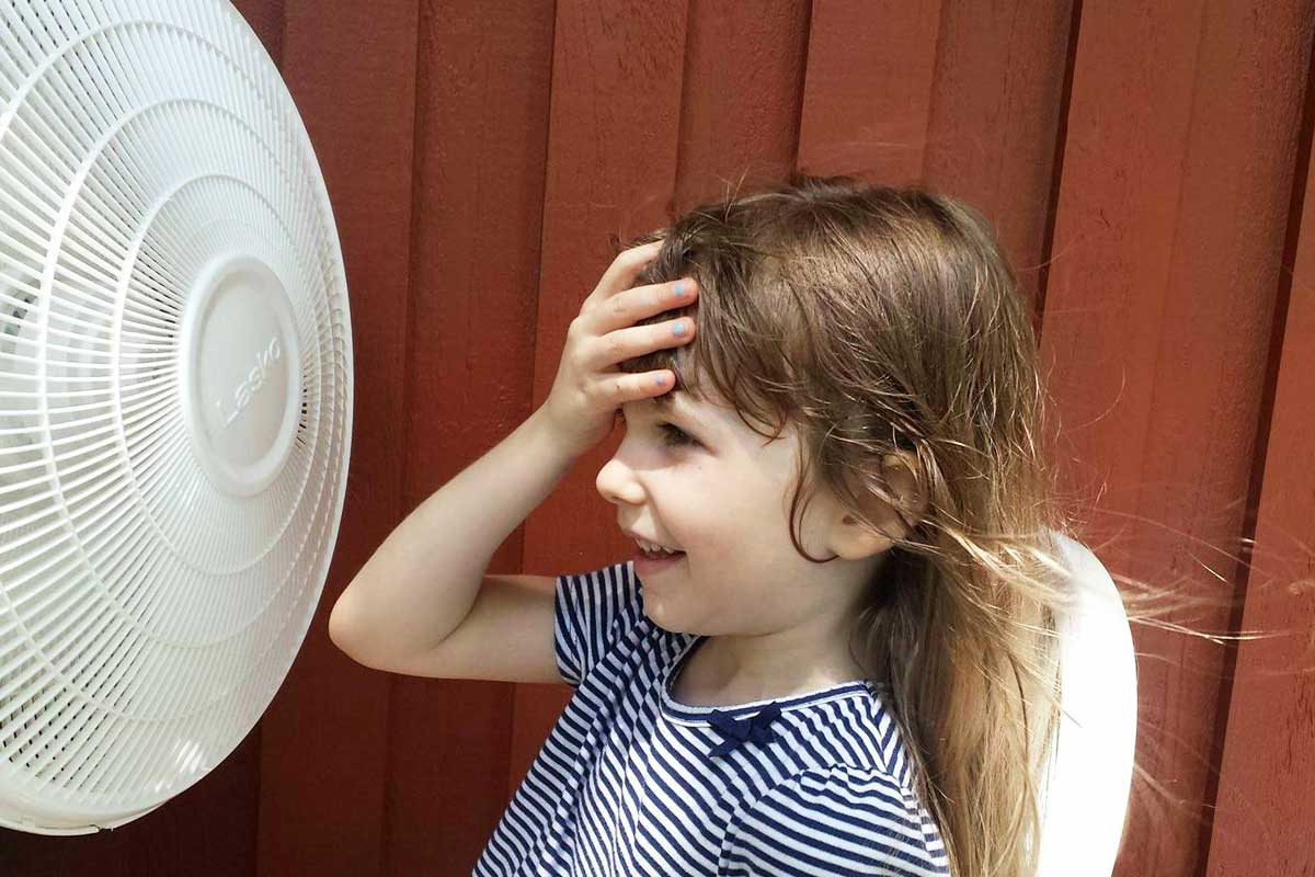 little girl cooling off in front of stand fan