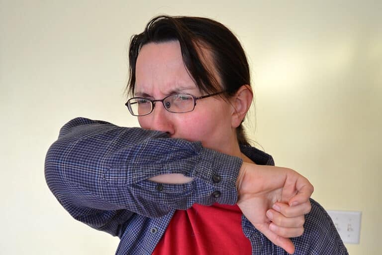 woman coughing in elbow