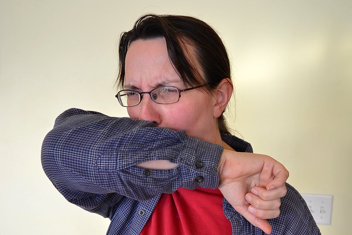woman coughing in elbow