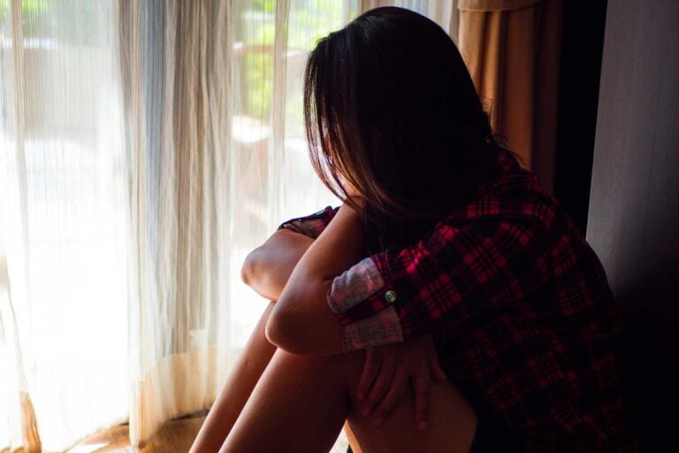 natural remedies for anxiety with woman in flannel shirt looking out a window